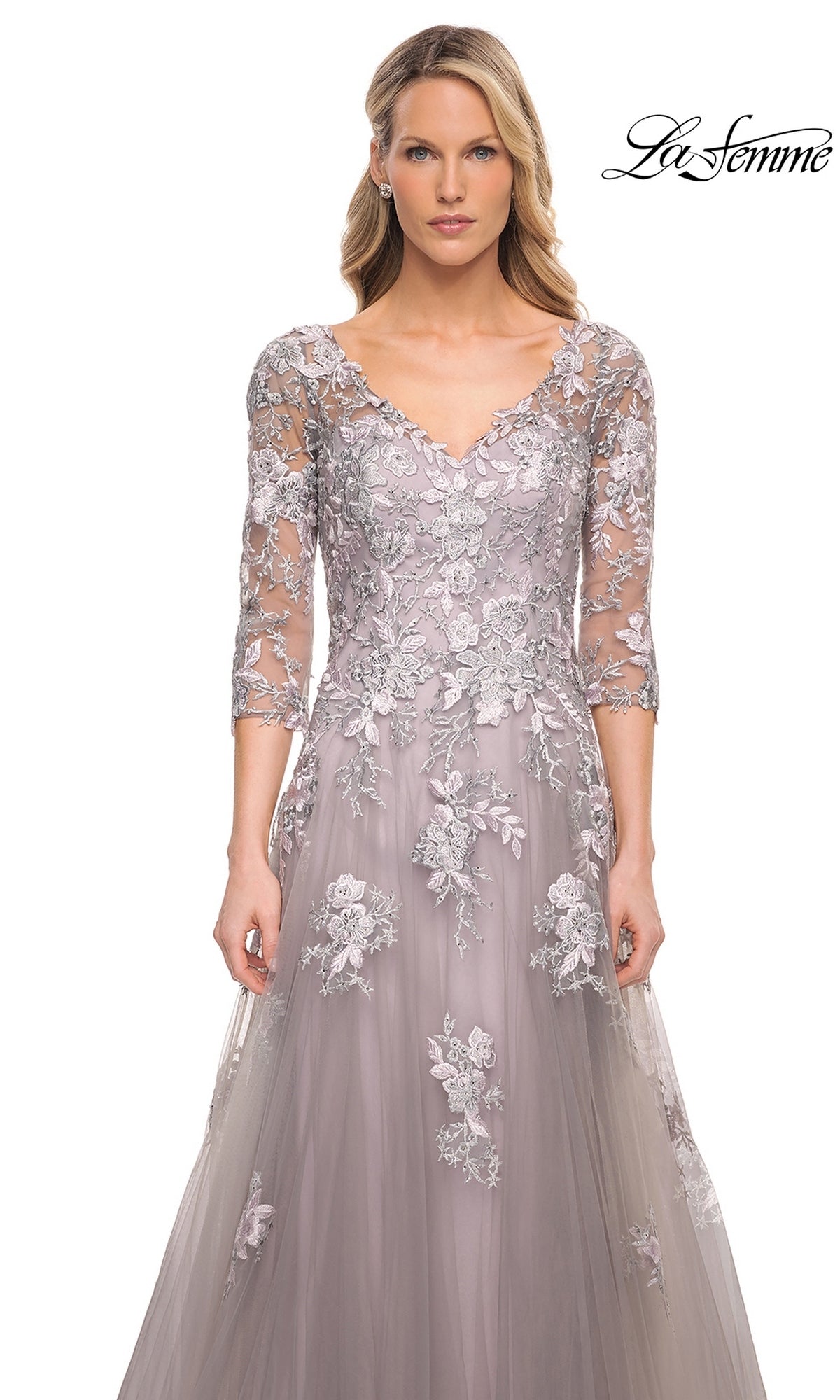 A woman wears a floor-length lavender Long Formal Dress: La Femme 30229, featuring a V-neckline, three-quarter length sleeves, and intricate floral lace appliques.